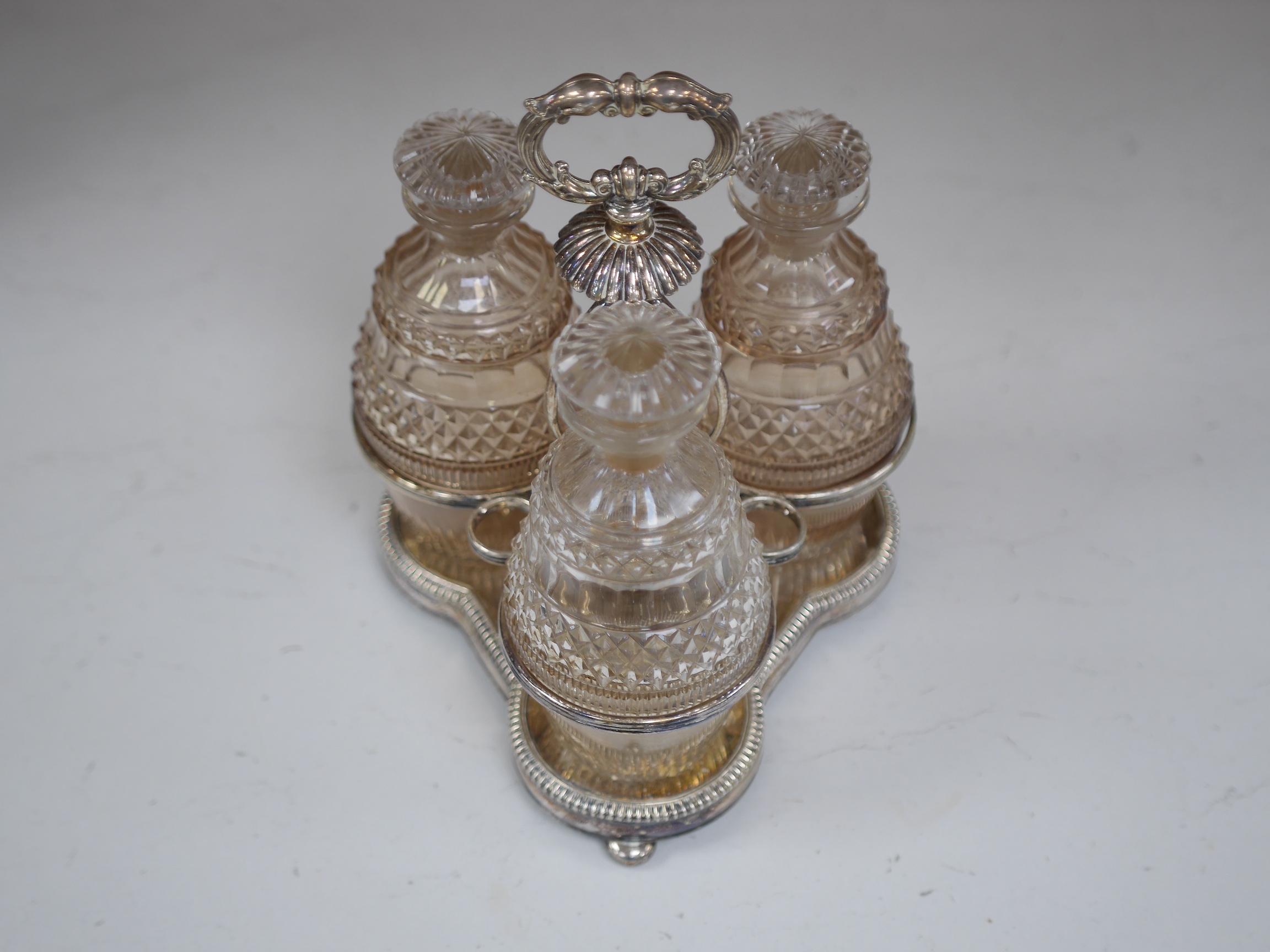 A cased silver plated three bottle liqueur stand, a cranberry decanter, sugar shaker and jam stand together with a green glass shaker, stand 27cm high (5). Condition - all items in good condition, box in need of a clean